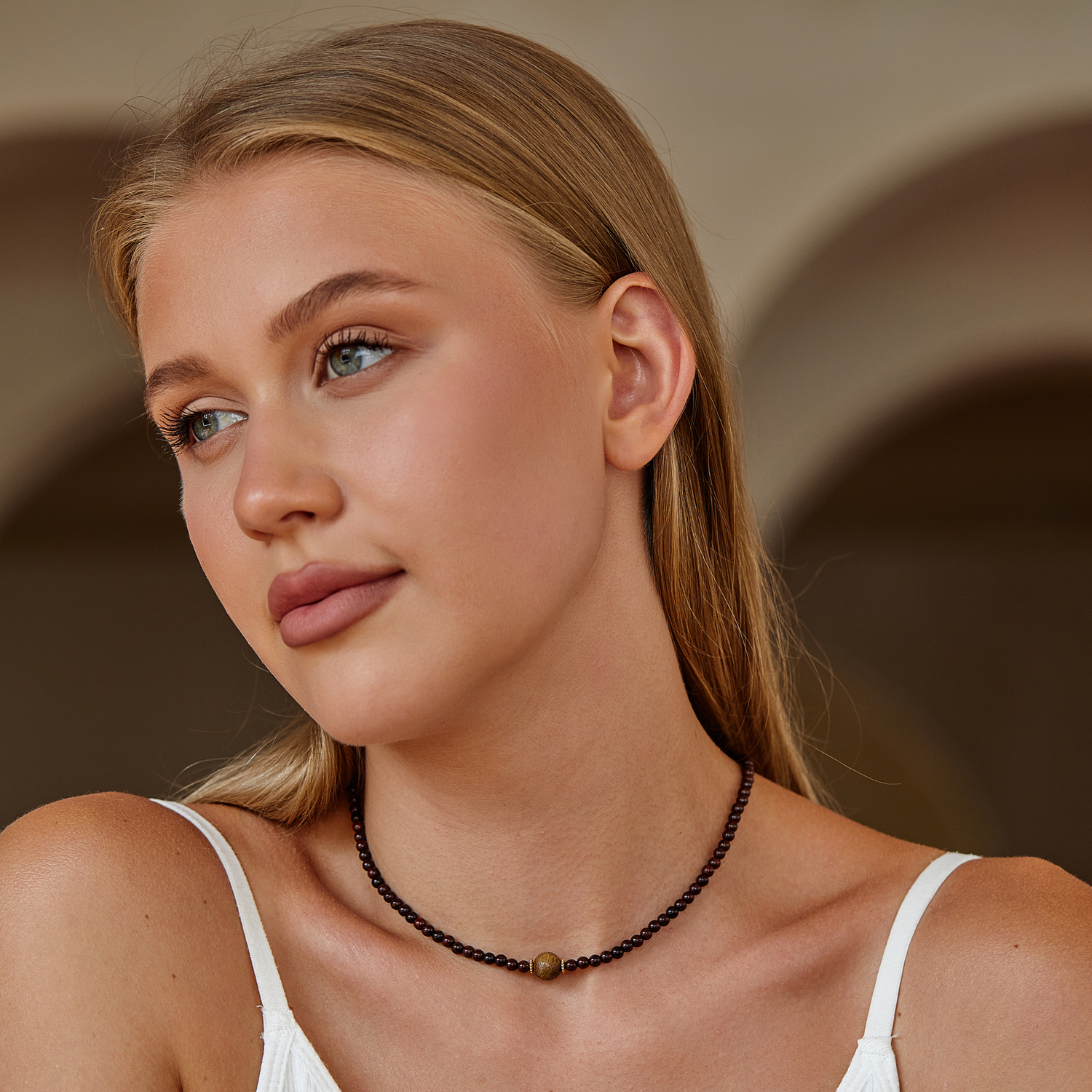 Woman wearing a sandalwood beaded necklace with a neutral background